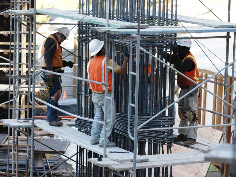 Construction crew standing on scaffolding working on steel pillars